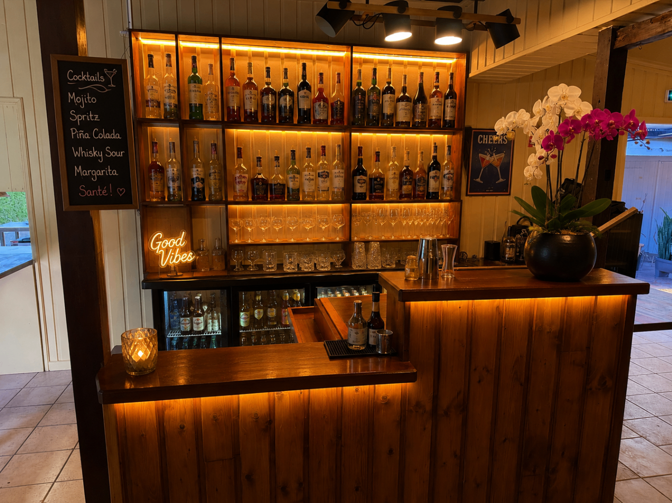 Bar en bois éclairé, bouteilles et orchidées